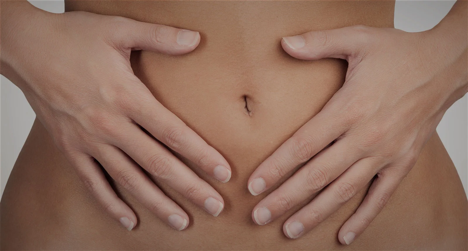 Mãos na frente de uma barriga feminina